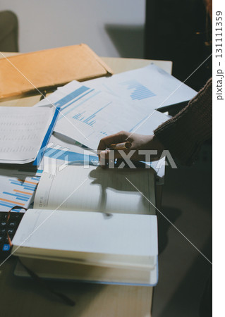 Close-up of businessman's hands making notes, mobiles, chart, desk, office 131111359