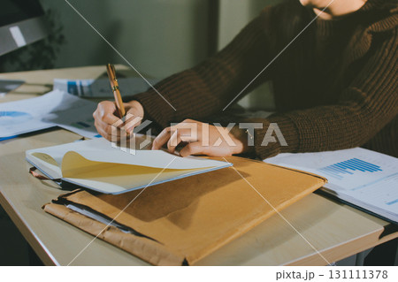 Close-up of businessman's hands making notes, mobiles, chart, desk, office Close-up of businessman's hands making notes, mobiles, chart, desk, office 131111378