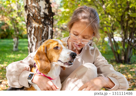 Young girl playing with her dog in the park during autumn. Joyful moments of pet ownership. Young girl playing with her dog in the park during autumn. Joyful moments of pet ownership. 131111486