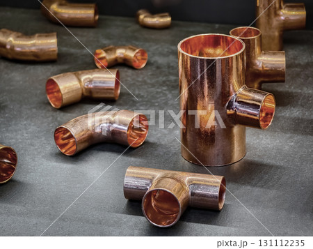 Copper plumbing fittings arranged on a dark surface showcasing varying shapes and sizes for construction and repair projects 131112235