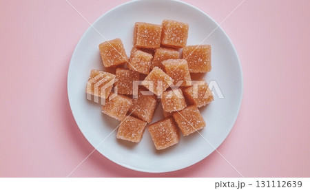 Brown sugar cubes natural sweetener for baking or drink on white plate in pink background Brown sugar cubes natural sweetener for baking or drink on white plate in pink background 131112639