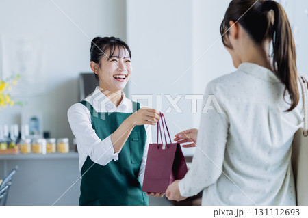 カフェで商品を渡す若い女性のスタッフ 131112693