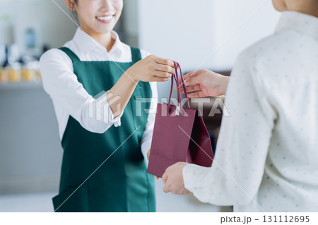 カフェで商品を渡す若い女性のスタッフ 131112695