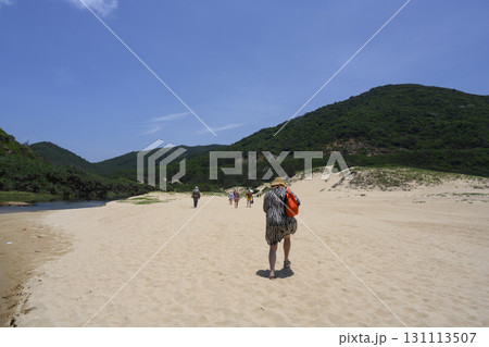 Tourists wander through a sandy valley along a stream between mountains in the heat of Vietnam Tourists wander through a sandy valley along a stream between mountains in the heat of Vietnam 131113507