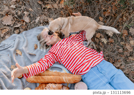 Young teenage girl lies on a plaid with friendly dog 131113696