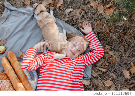 Young girl lies on a plaid with friendly dog outdoor Young girl lies on a plaid with friendly dog outdoor 131113697