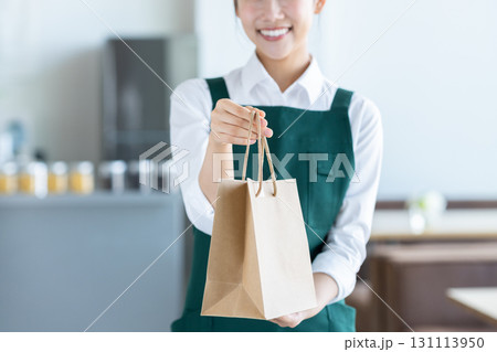 商品を渡す若い女性の店員 商品を渡す若い女性の店員 131113950