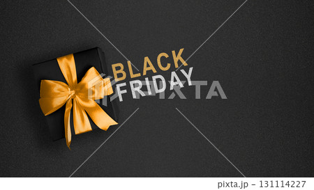 Closeup view of a black gift box with golden ribbon and text of Black Friday on a black background. Copy space. Flat lay. Black Friday sale concept Closeup view of a black gift box with golden ribbon and text of Black Friday on a black background. Copy space. Flat lay. Black Friday sale concept 131114227