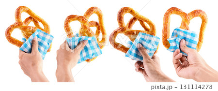 Collection set of human hands holding a salty baked brown pretzel with a blue checkered tablecloth or napkin isolated over a white background. Oktoberfest festival 131114278