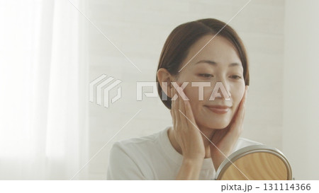 鏡を見ながら肌の調子を確認する40代日本人女性 131114366