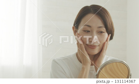 鏡を見ながら肌の調子を確認する40代日本人女性 131114367