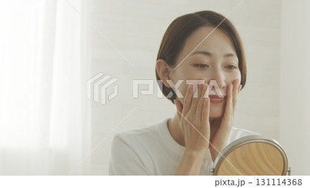 鏡を見ながら肌の調子を確認する40代日本人女性 131114368