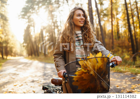 Beautiful woman in stylish clothes with bicycle walking in autumn park Woman walking in sunny forest Beautiful woman in stylish clothes with bicycle walking in autumn park Woman walking in sunny forest 131114382