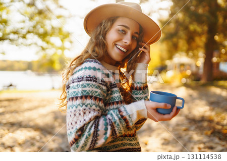 Lady drinks from thermo mug of coffee in nature. Warm up in sunny autumn forest. Travel, adventure. Lady drinks from thermo mug of coffee in nature. Warm up in sunny autumn forest. Travel, adventure. 131114538