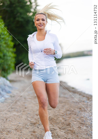 Woman Running Outdoors Along Beach Path Using Wearable Fitness Technology Woman Running Outdoors Along Beach Path Using Wearable Fitness Technology 131114732