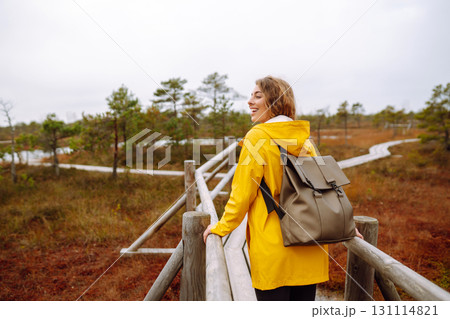 Portrait of happy woman walking along path among marsh nature. Concept of travel. Active lifestyle. Portrait of happy woman walking along path among marsh nature. Concept of travel. Active lifestyle. 131114821