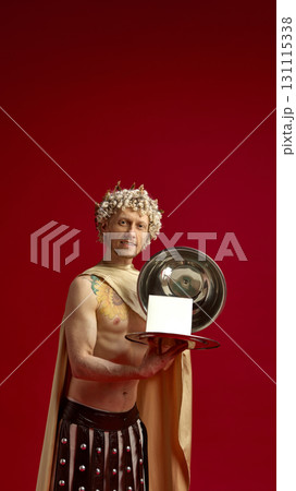 Man in Caesar costume smiling while holding silver tray with copy space box 131115338