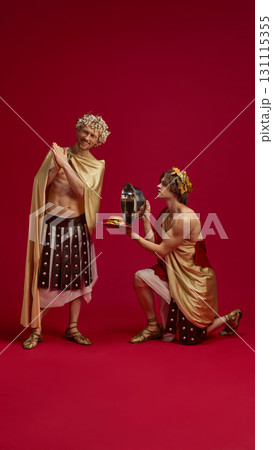 Young student kneels in front of mature man serving fast food on tray with cloche Young student kneels in front of mature man serving fast food on tray with cloche 131115355