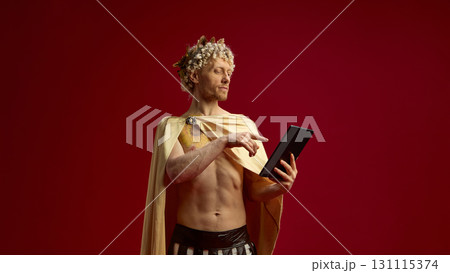 Man in Roman toga as Caesar using digital tablet with serious expression 131115374