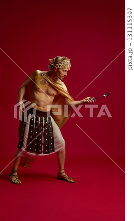 Man in Caesar costume posing with fork like gladiator weapon 131115397