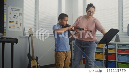 Talented Boy Playing Violin During Music Lesson. Teacher Supporting and Teaching Future Musician Talented Boy Playing Violin During Music Lesson. Teacher Supporting and Teaching Future Musician 131115779