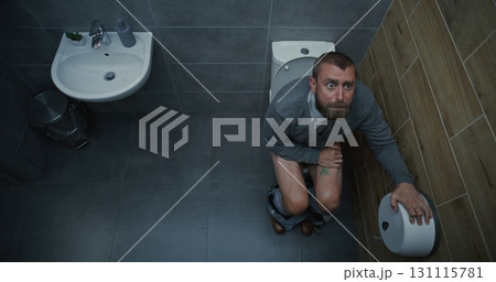 Man Taking Off Pants, Sitting on Toilet, Experiencing Diarrhea and Digestive Discomfort Man Taking Off Pants, Sitting on Toilet, Experiencing Diarrhea and Digestive Discomfort 131115781