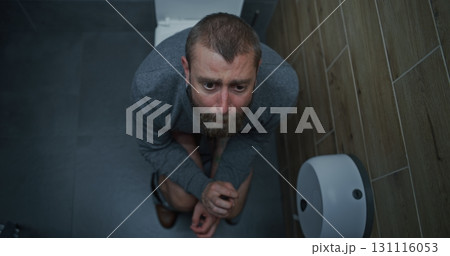Businessman with Tense Facial Expression Suffering from Diarrhea and Indigestion, Sitting on the Toilet Businessman with Tense Facial Expression Suffering from Diarrhea and Indigestion, Sitting on the Toilet 131116053