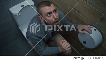Businessman with Tense Facial Expression Suffering from Diarrhea and Indigestion, Sitting on the Toilet Businessman with Tense Facial Expression Suffering from Diarrhea and Indigestion, Sitting on the Toilet 131116054