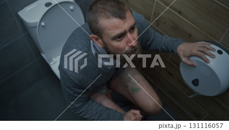 Man with Tense Facial Expression Sitting on Toilet, Suffering from Diarrhea Man with Tense Facial Expression Sitting on Toilet, Suffering from Diarrhea 131116057