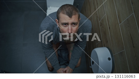 Businessman with Tense Facial Expression Suffering from Diarrhea and Indigestion, Sitting on the Toilet Businessman with Tense Facial Expression Suffering from Diarrhea and Indigestion, Sitting on the Toilet 131116063
