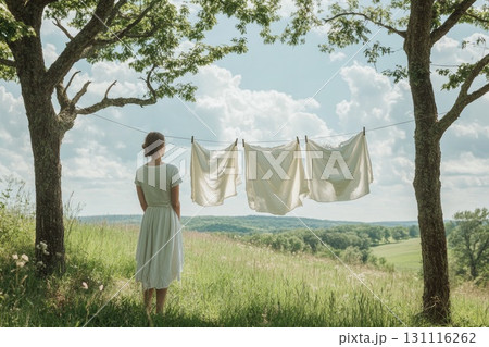 Woman standing by laundry on clothesline in nature Woman standing by laundry on clothesline in nature 131116262