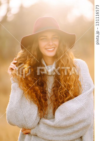 Stylish woman in sweater and hat enjoys autumn nature. People, freedom, lifestyle, travel concept. Stylish woman in sweater and hat enjoys autumn nature. People, freedom, lifestyle, travel concept. 131116573