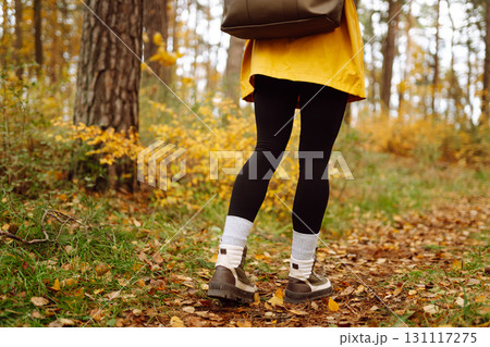 Female legs in boots walking through fallen trees in autumn park. Nature, travel concept. 131117275