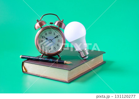 Alarm clock ,Light bulb with Fountain pen on old book background.Education concept. Alarm clock ,Light bulb with Fountain pen on old book background.Education concept. 131120277