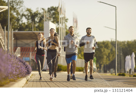 Group of young and sportive men and women jogging outdoors 131121404