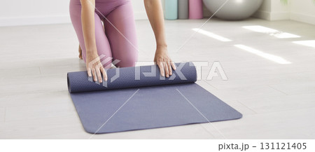 Unknown woman rolling out fitness mat before practicing yoga or meditation, preparing for pilates 131121405