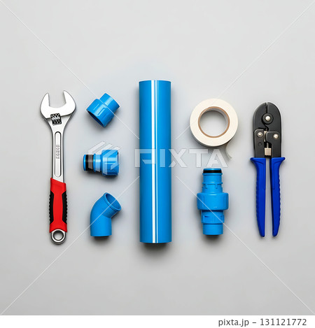 Plumbing tools and fittings laid out neatly including a wrench, blue pipe, fittings, tape, and pliers. Blue and red handle accents on tools, creating a vibrant contrast 131121772