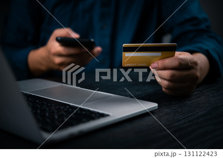 Hand holding credit card and mobile phone for online payment. Digital finance transaction and banking concept for shopping or mobile purchase through e-commerce platforms. Hand holding credit card and mobile phone for online payment. Digital finance transaction and banking concept for shopping or mobile purchase through e-commerce platforms. 131122423