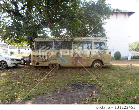 An Old Painted Bus Parked in a Grassy Yard Under a Tree with a House in the Distance An Old Painted Bus Parked in a Grassy Yard Under a Tree with a House in the Distance 131122453