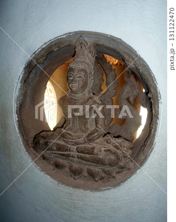 A Stone Buddha Carving in a Circular Wall Niche with Intricate Details in a Temple Setting A Stone Buddha Carving in a Circular Wall Niche with Intricate Details in a Temple Setting 131122470