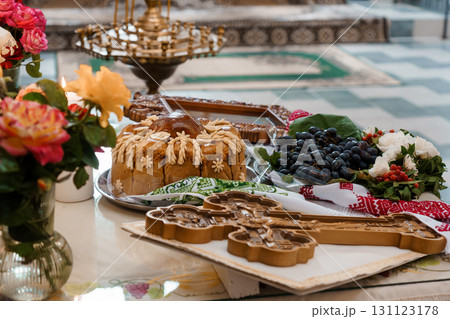 Ukrainian Traditional Easter Bread Kulich with Flowers, Grapes, and Pastry Cutters on Marble Table Ukrainian Traditional Easter Bread Kulich with Flowers, Grapes, and Pastry Cutters on Marble Table 131123178