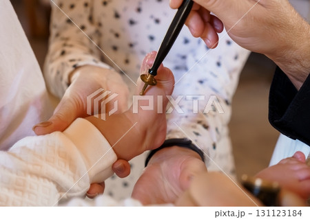 Baby Foot Reflexology Session with Practitioner Using Gold Instrument, White Textured Clothing and Soft Lighting 131123184