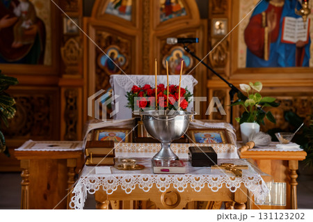 Orthodox Church Altar Scene with Red Roses, Silver Bowl, Candles, and Icons in Warm Lit Gold Interior. Orthodox Church Altar Scene with Red Roses, Silver Bowl, Candles, and Icons in Warm Lit Gold Interior. 131123202