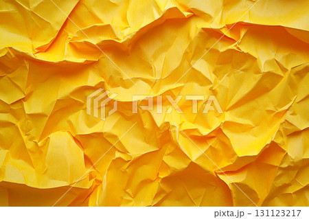 A vibrant yellow, close-up view of a crumpled piece of paper, showing a highly textured surface with numerous folds, creases, and shadows. 131123217