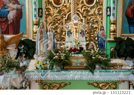 Elaborate Catholic Altar Decorated with Statues, Flowers, and Gold Accents. Vivid Religious Scene in Green Church Interior Elaborate Catholic Altar Decorated with Statues, Flowers, and Gold Accents. Vivid Religious Scene in Green Church Interior 131123221