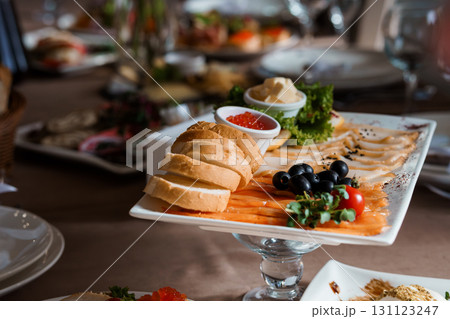 Sumptuous Mezze Platter with Salmon, Bread, Caviar and Olives: Gourmet Food Presentation on Dark Table Setting, Rich Colors Sumptuous Mezze Platter with Salmon, Bread, Caviar and Olives: Gourmet Food Presentation on Dark Table Setting, Rich Colors 131123247