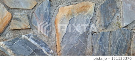 This wall features a striking arrangement of natural stone pieces with a variety of colors and textures. It serves as an attractive backdrop, adding character to any space. 131123370