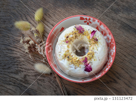 a Pistachio & Rose Baked Doughnuts featuring a white glaze and generous decoration of crushed pistachios and dried rose petals 131123472