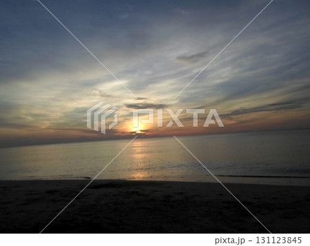 Sunset with Sun Touching Horizon Over Calm Ocean and Sandy Beach Sunset with Sun Touching Horizon Over Calm Ocean and Sandy Beach 131123845