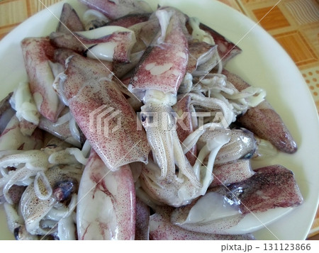 A White Plate Filled with Fresh Raw Squid on a Checkered Tablecloth in a Kitchen Setting 131123866